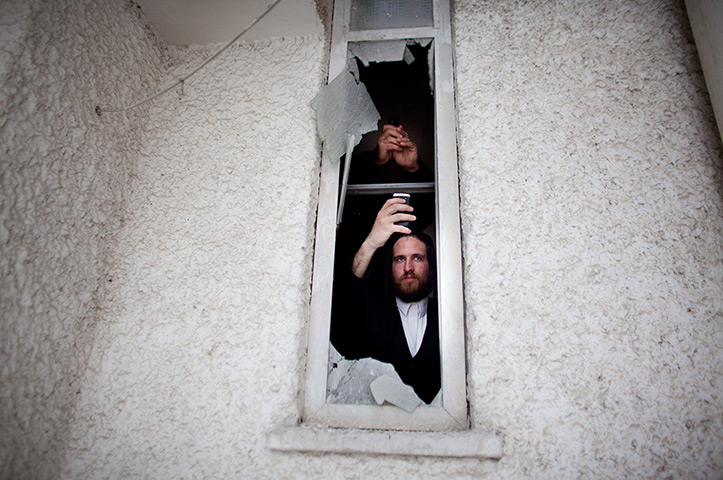24 hours in pictures: An Israeli man looks out of a window after a rocket attack from Gaza Strip