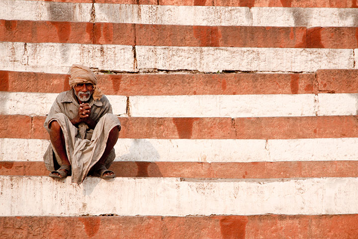 In Pictures: man perched on striped steps along the banks of the Ganges
