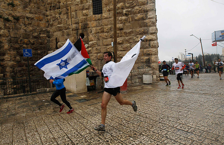Jerusalem Marathon: A runner holds an Israeli and Palestinian flag during Jerusalem Marathon
