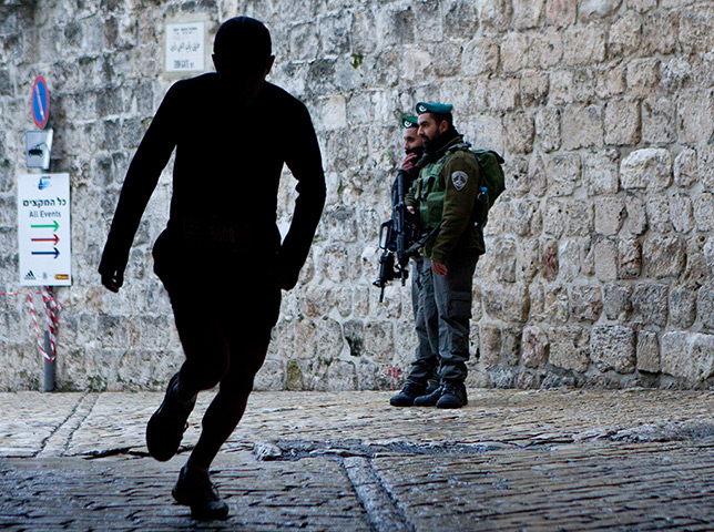 Jerusalem Marathon: Two Israeli Border Police watch as a runner as he enters the Zion Gate area