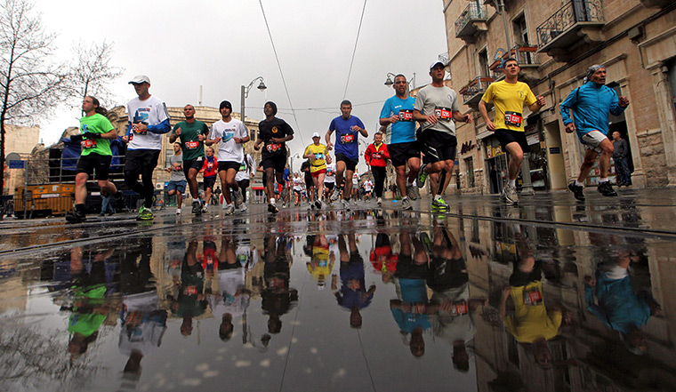 Jerusalem Marathon: Marathon runners passing Jaffa Street are reflected in the wet road