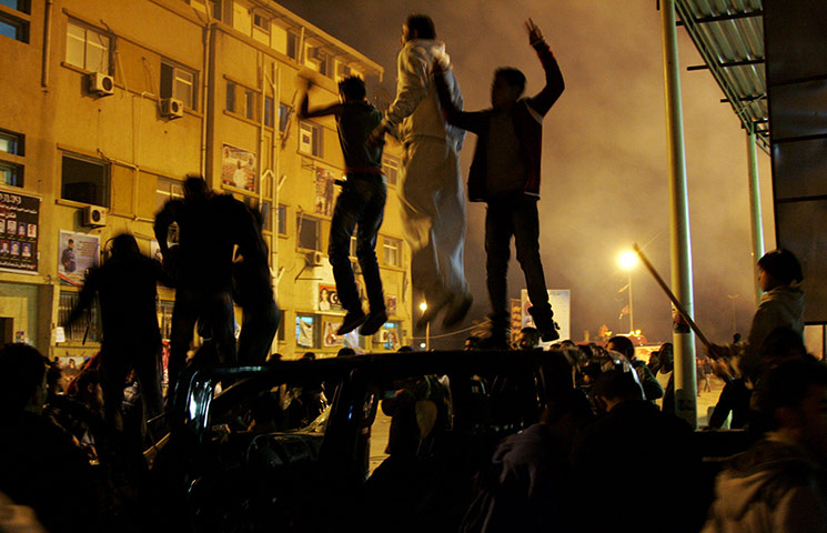 24 hours: Protesters jump on a car during clashes in Benghazi, Libya