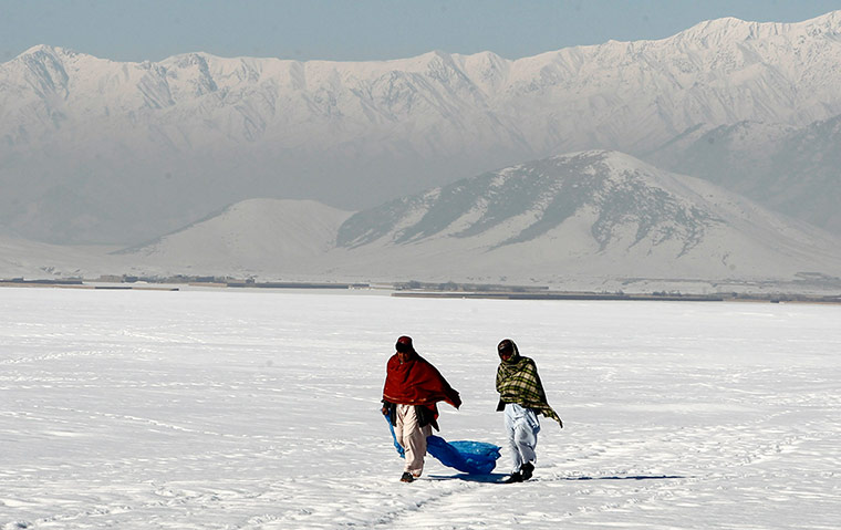 Snow: Afghan residents walk on a snow covered field