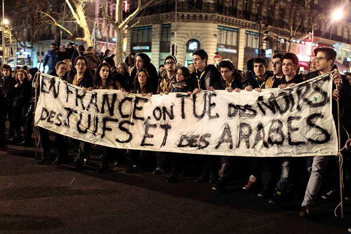 Toulouse shooting: Youths hold a banner which reads: In France we kill Blacks, Jews and Arabs