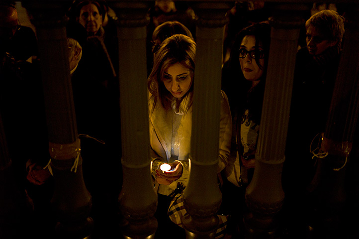 24 hours in pictures: Paris, France: A woman pays her respects front of candles