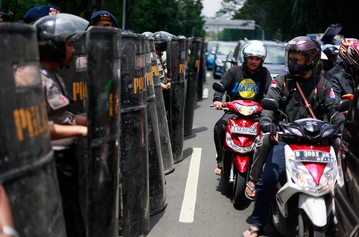 24 hours in pictures: Motorists ride past Indonesian riot police officers standing guard 