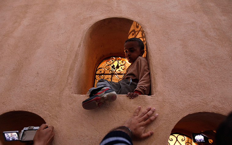 24 hours in pictures: A boy watches mourners gathering for the interment of Pope Shenouda III