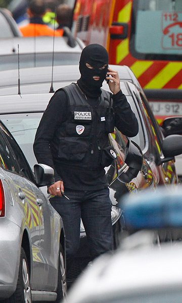 Toulouse siege: A police officer talks on a phone next to the building where a suspect is