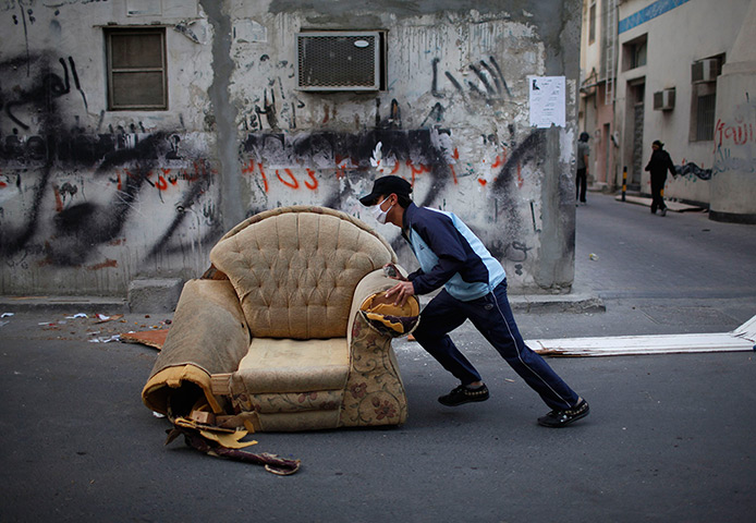 24 hours: Sanabis, Bahrain: An anti-government protester pushes an armchair 
