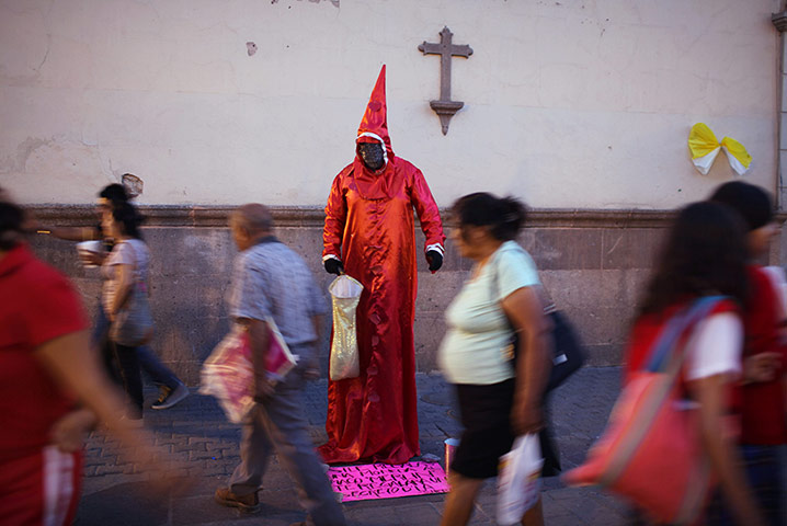 24 Hours: Leon, Mexico: People walk past a street artist dressed as a magician