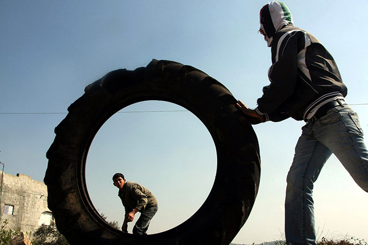 24 hours: Kfar Kadum, Israel: Palestinian protester rolls a tyre to burn it