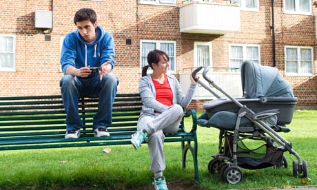 Poor, uncommunicative teenage couple with pram in front of council flats