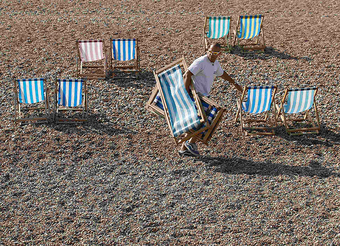 Warm Weather: An attendant puts out deckchairs on Brighton beach