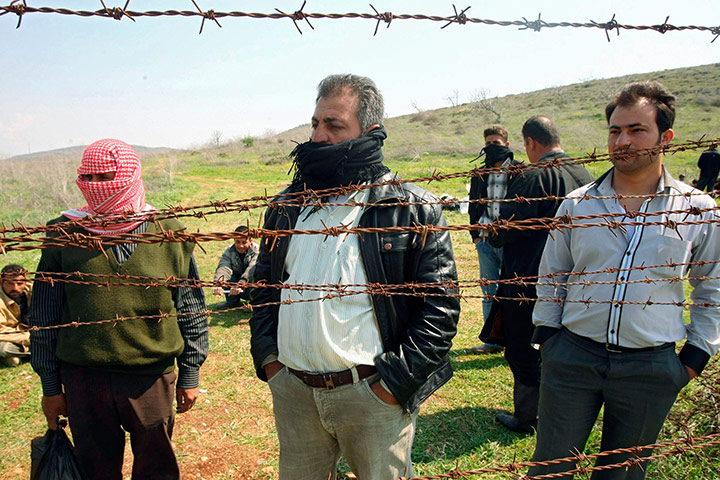 Syrian Refugees: Syrian refugees look through barbed