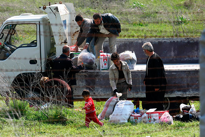 Syrian Refugees: Syrian refugees look  through a barbed wire fence