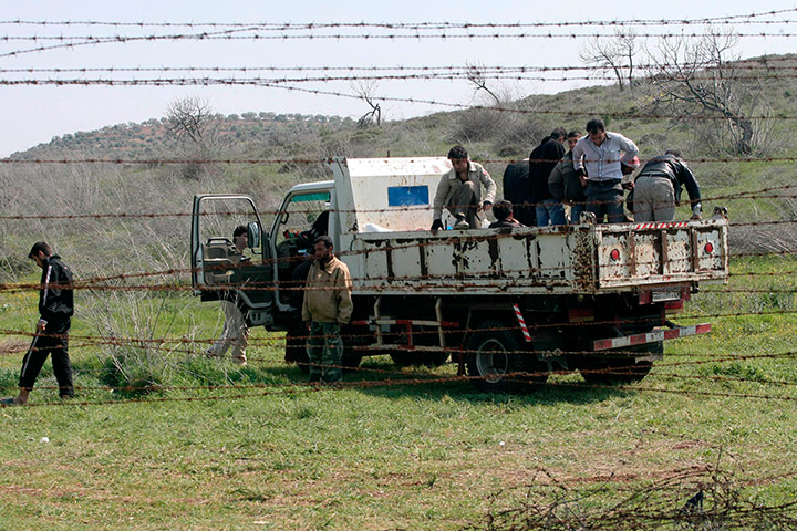 Syrian Refugees: Syrian refugees look on March 27, 2012 through a barbed wire fence
