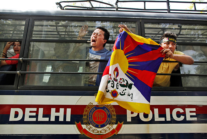 24 hours in pictures: A Tibetan exile waves from inside a police vehicle after being detained