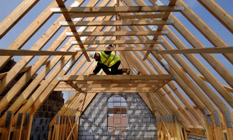 A builder surveying the roof timbers of a new house under construction
