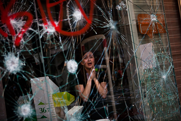24 hours in pictures: Barcelona, Spain: Mirian Burrueco stands behind broken glass of her shop