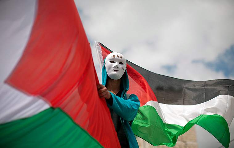 Land Day protests: A Palestinian man waves his national flag during clashes at the Kalandia 