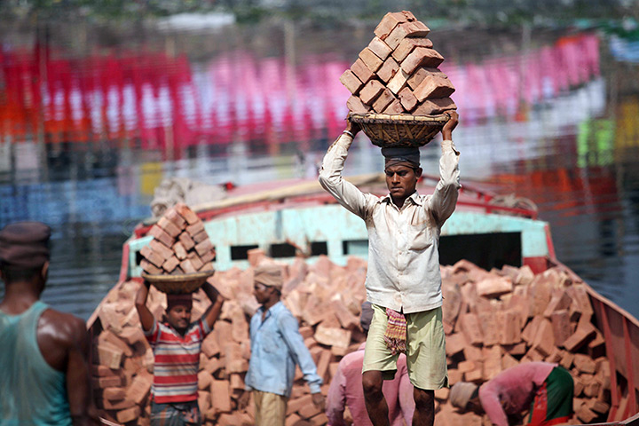 24 hours: Dhaka, Bangladesh: Labourers carry bricks as they unload a cargo boat