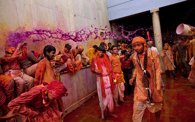 Lathmar Holi : An Indian Hindu worshipper throws a bucket of coloured water on others 