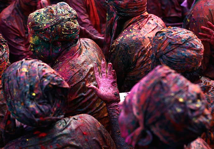 Lathmar Holi : Men daubed in coloured powder sing a hymn at a temple 