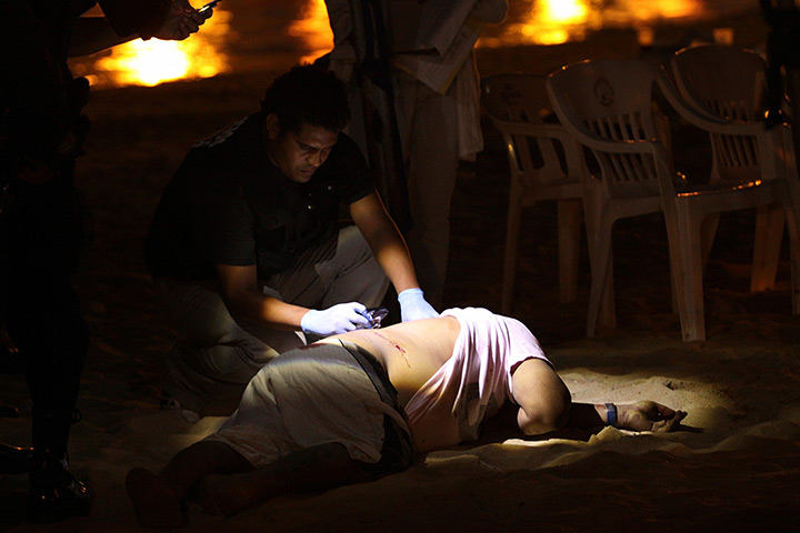 24 hours in pictures: Acapulco, Mexico: A forensic specialist inspects the body of a slain man
