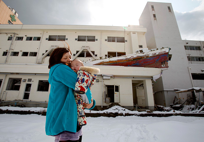 24 hours: Minamisanriku, Japan: A woman holds her son in front of the town hospital