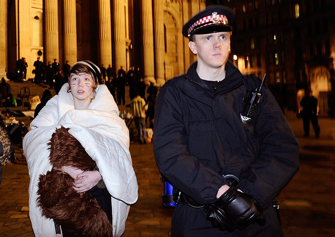 Women protesting: A woman keeps warm as riot police remove protesters from the Occupy 