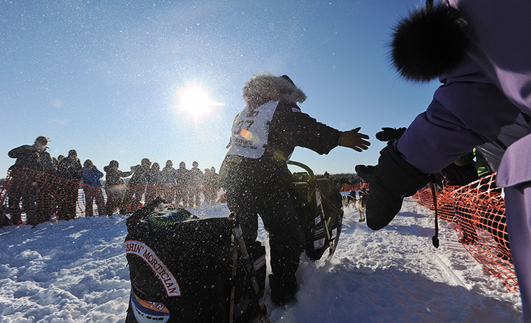  Iditarod Sled Dog Race: Scott Janssen reaches out towards fans at the official restart in Willow