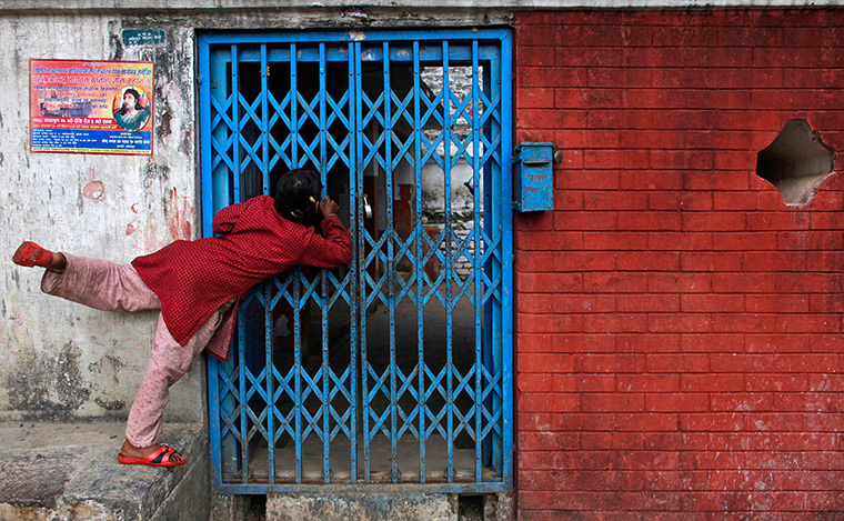 24 hours in pictures: Godawari, Nepal: A girl looks through a gate of a temple