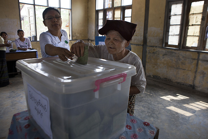 Burma elections count: A Burmese woman receives help putting her ballot in the box