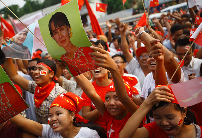 Burma elections count: Supporters of the NLD party cheer watching increasing votes on a screen