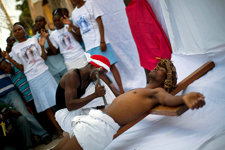 Haiti - A longer view: An actor lies on a wooden cross during the reenactment of the crucifixion