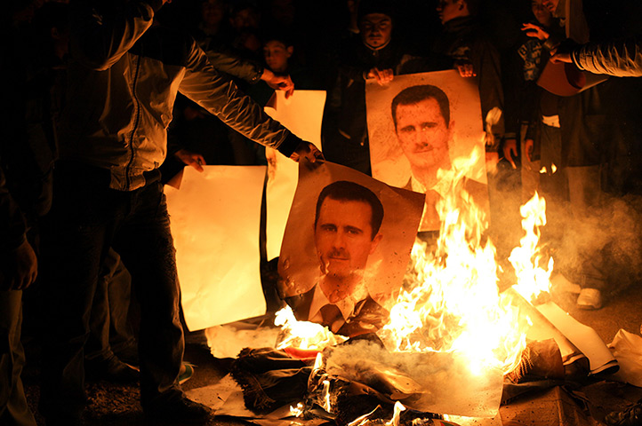 Aleppo, Syria: Young men burn posters of Bashr al-Assad during a night demonstration