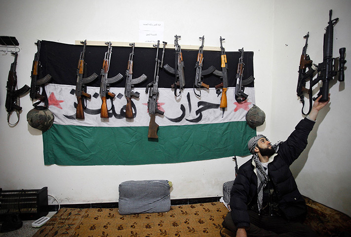 Aleppo, Syria: A rebel of the Free Syrian Army reaches for his weapon in a safehouse