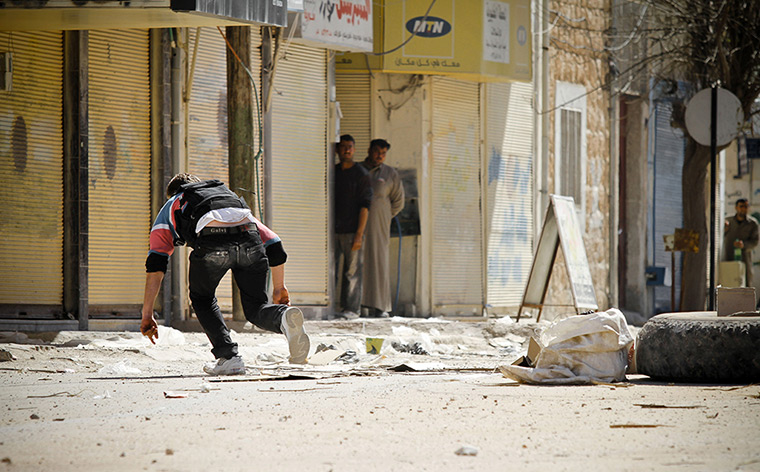 Aleppo, Syria: A rebel of the Free Syrian Army runs after placing an IED in the road 