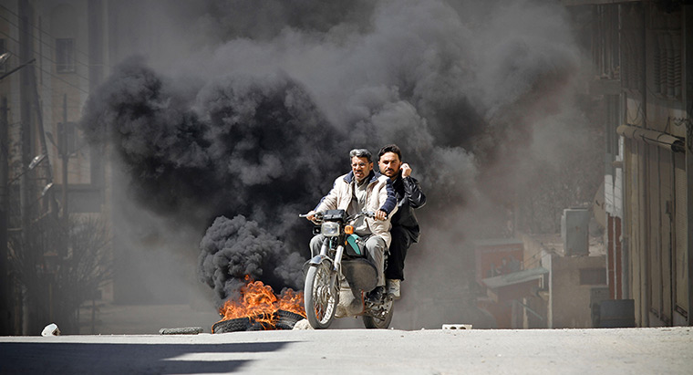 Aleppo, Syria: Citizens of Saraquib City flee the town on motorcycle while car tyres burn