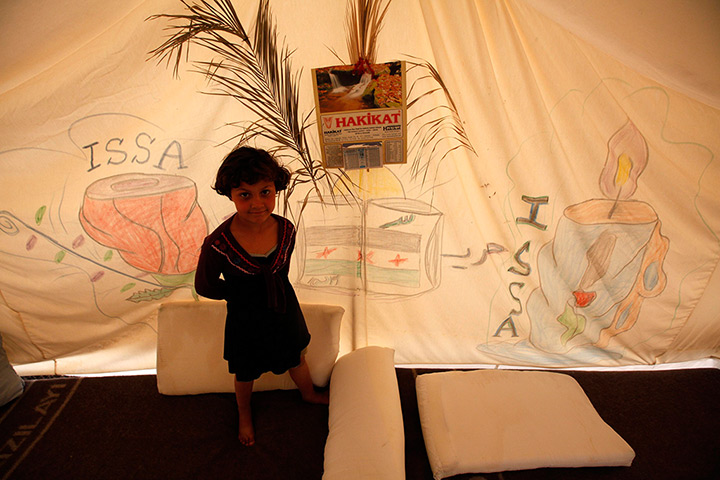 Boynuyogun refugee camp: A Syrian refugee stands beside a drawing on a tent at Boynuyogun camp
