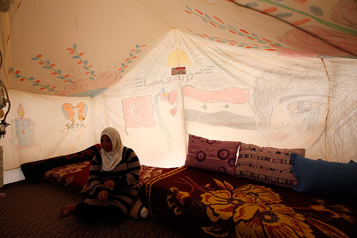 Boynuyogun refugee camp: A Syrian refugee sits beside a drawings on a tent canvas at Boynuyogun camp