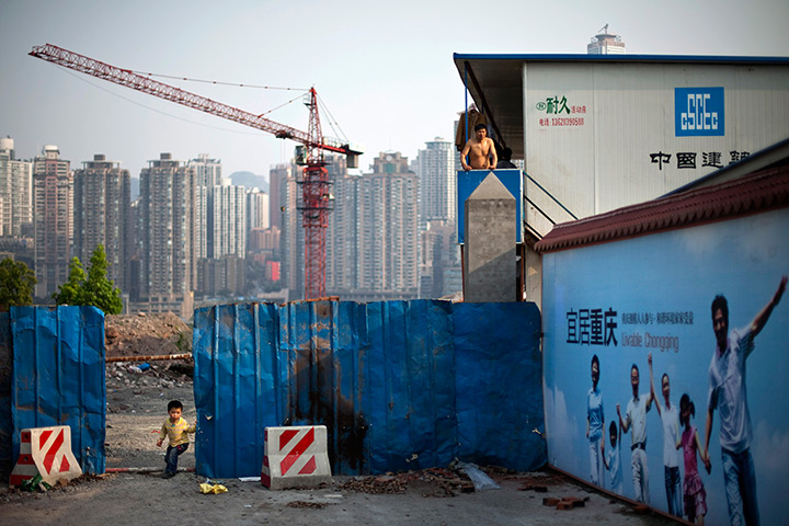 24 hours: Chongqing city, China: A migrant worker stands at a construction site 