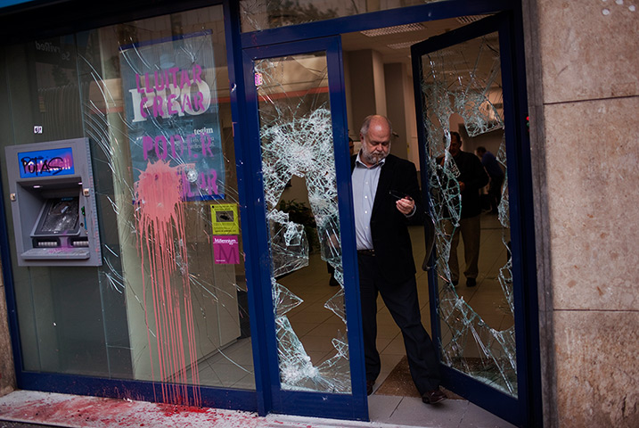 Week in Business: A man leaves a bank stormed by demonstrators in Barcelona