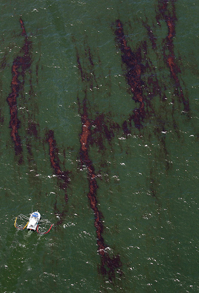 Week in Business: A boat pulls absorbent materials after the Deepwater Horizon oil spill 