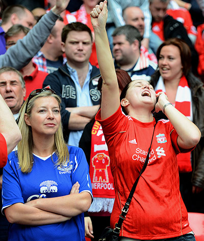 FA CUP SEMI:  A Liverpool fan celebrates as an Everton fan looks dejected 