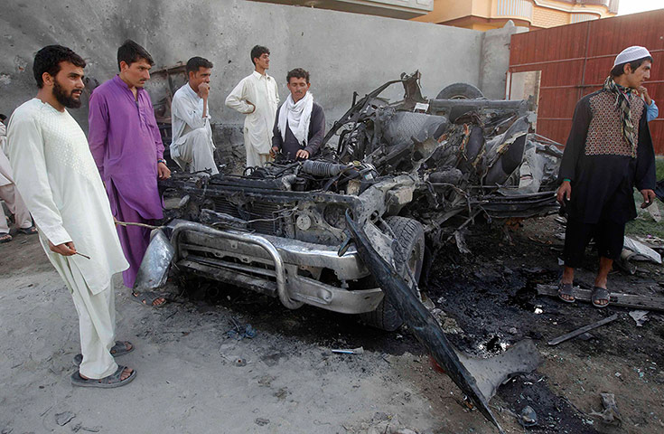 Afghanistan attacks: Afghan men stand around the wreckage of a car used by a suicide attacker