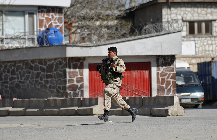 Afghanistan attacks: An Afghan security officer runs to a building in Kabul