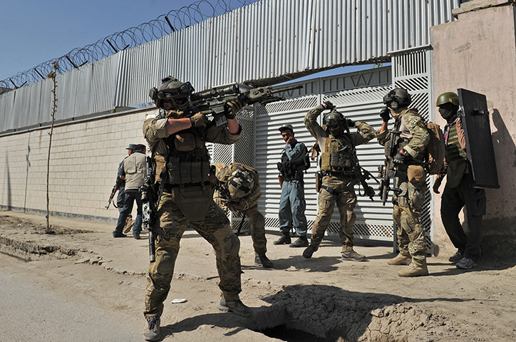 Afghanistan violence: April 15: A member of the foreign forces points his gun towards a building