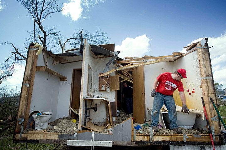 Tornado damage: A man picks up debris from a damaged home in Thurman, Iowa