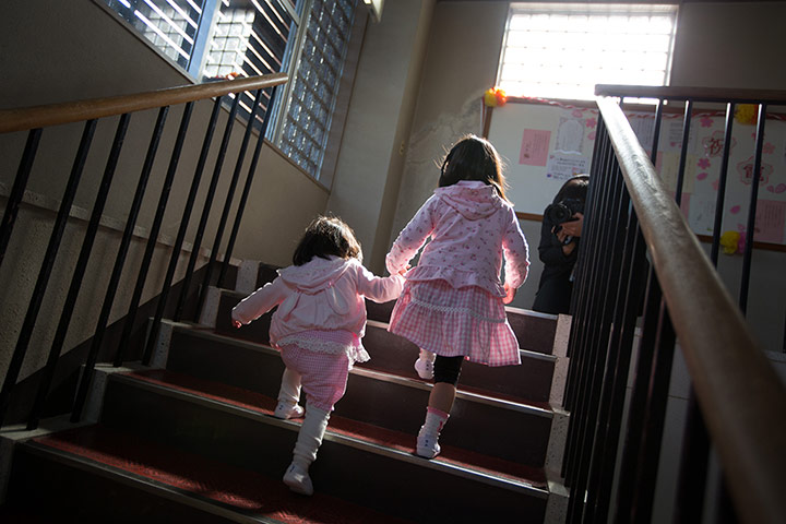 Kawauchi, Japan: Yume Nakamaru, 4 helps her younger sister Hime, 2 on the stairs